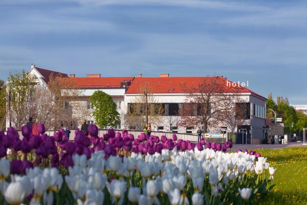 ein Feld aus lila und weißen Tulpen vor einem Gebäude in der Unterkunft Strandhotel Alte Donau in Wien