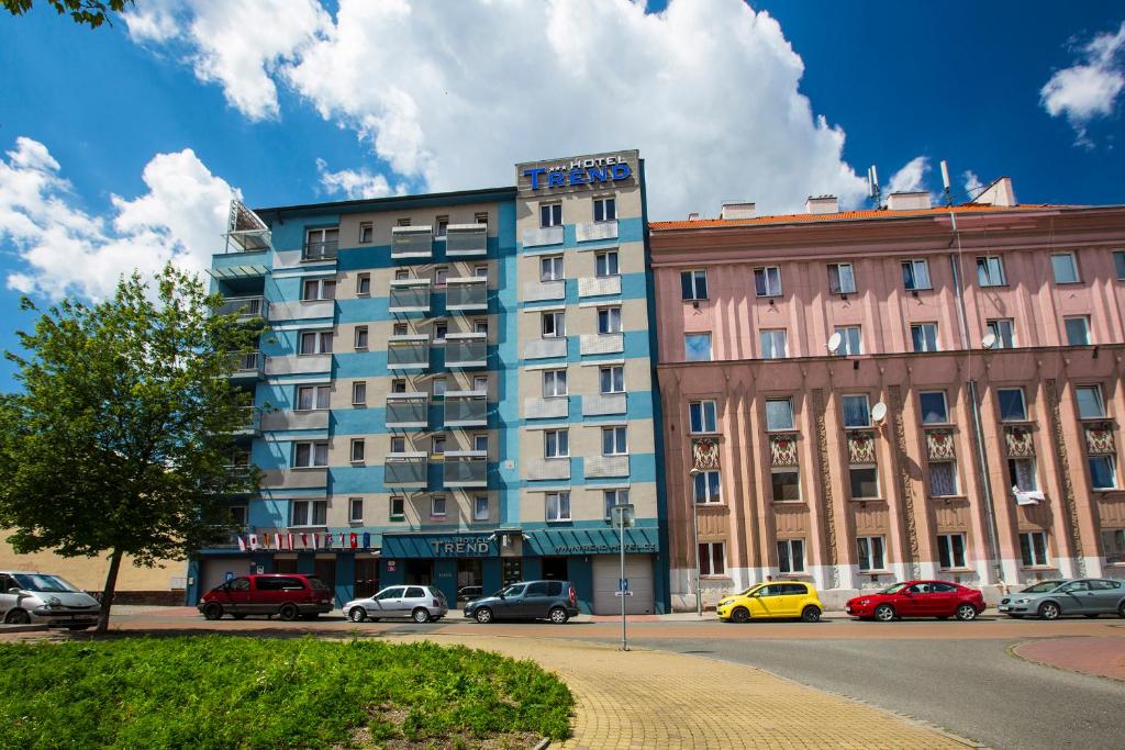 un edificio blu con auto parcheggiate in un parcheggio di Hotel Trend a Plzeň