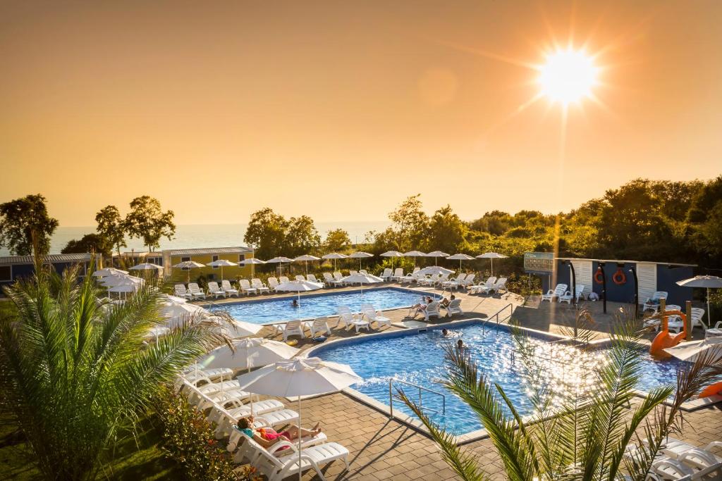 einen großen Pool mit weißen Stühlen und Sonnenschirmen in der Unterkunft Aminess Maravea Camping Resort Holiday Homes in Novigrad Istria