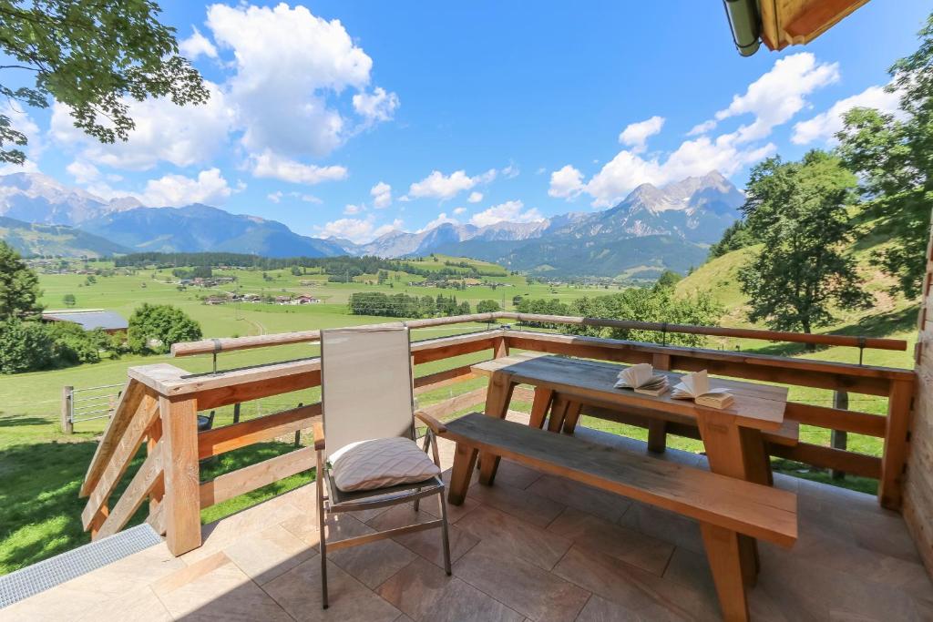 uma mesa e cadeira de madeira numa varanda com montanhas em Chalet Die Mühle em Saalfelden am Steinernen Meer