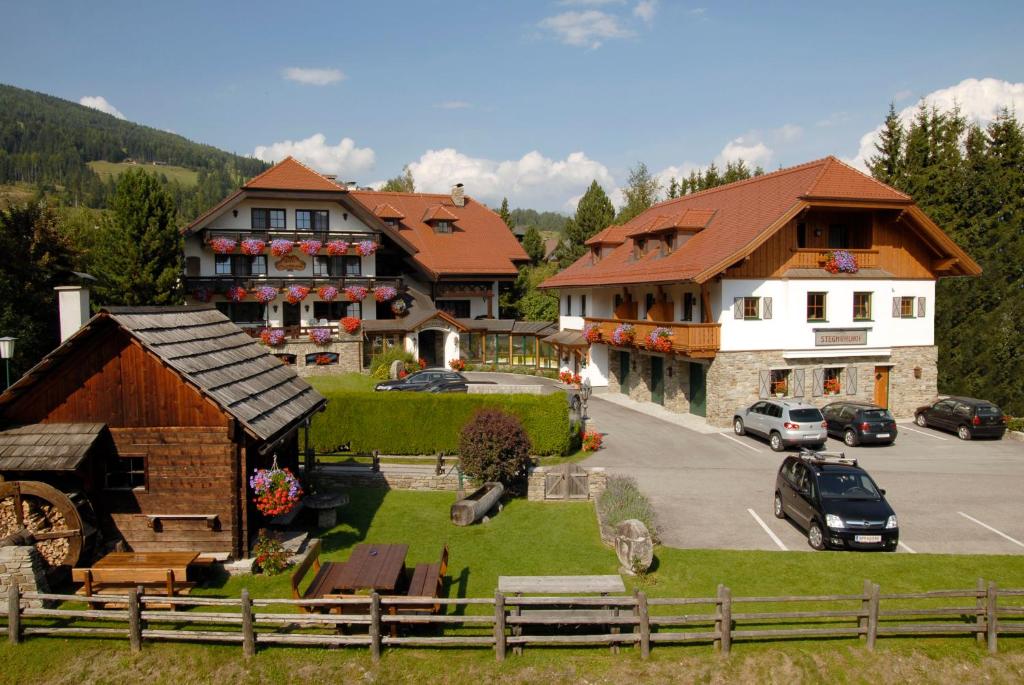 un grupo de edificios y un aparcamiento con coches en Hotel Stegmühlhof, en Mauterndorf