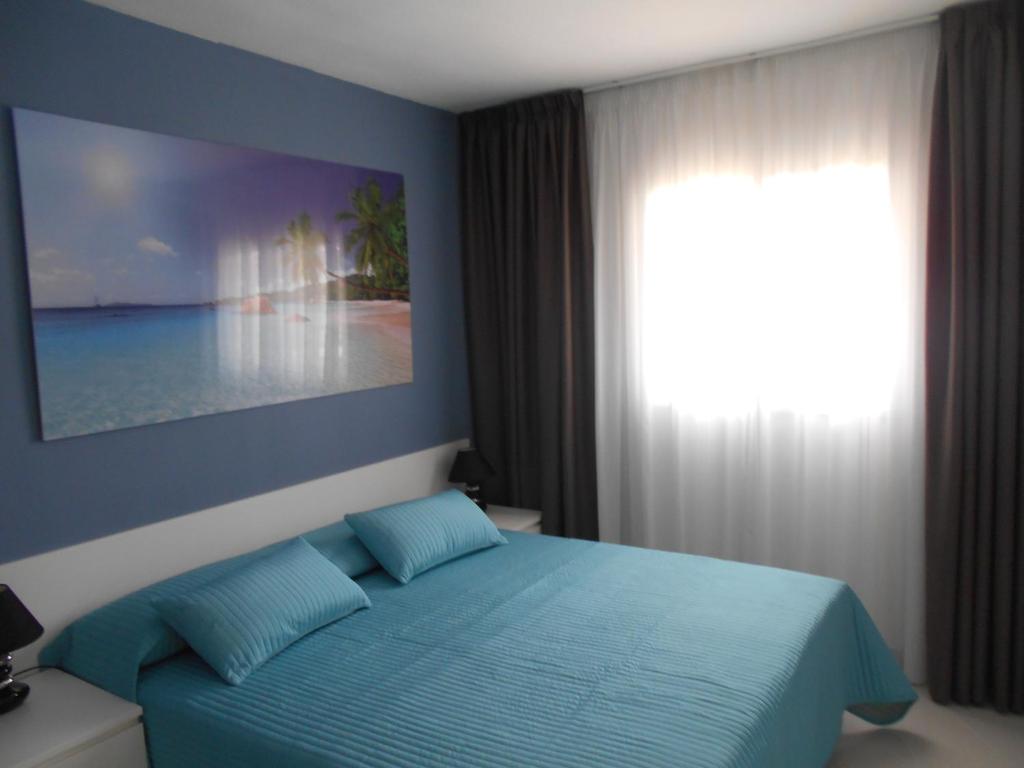 una camera con un letto blu e una finestra di Orlando Apart ad Adeje