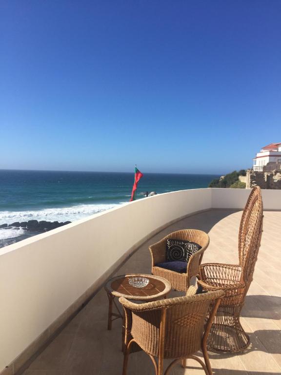 Un balcón con sillas, una mesa y el océano en Residencial Real Guest House, en Sintra