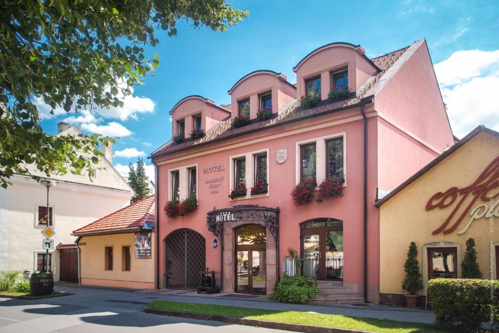 a pink building on the side of a street at Hotel Bojnický vínny dom in Bojnice