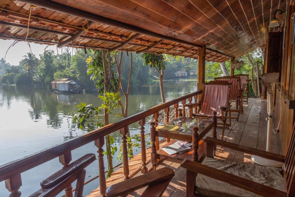 a porch with chairs and a view of a river at Malayalam Lake Resort in Alleppey