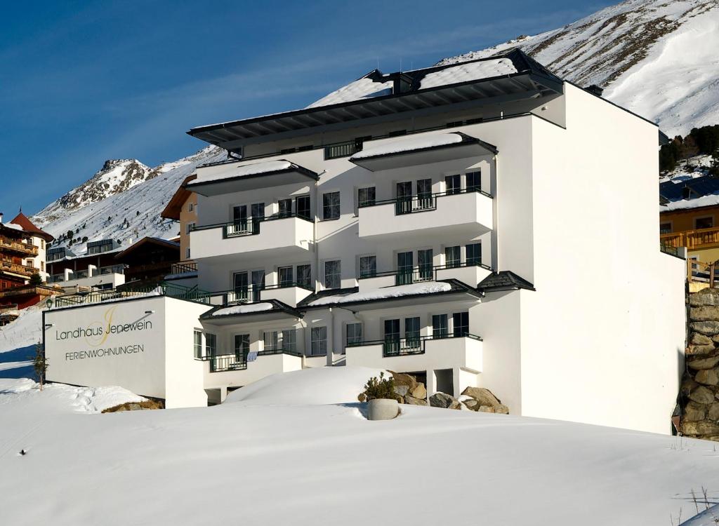 um edifício branco na neve com uma montanha em Landhaus Jenewein em Obergurgl