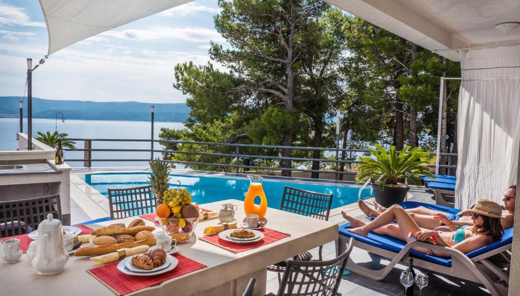 une femme assise sur une terrasse avec une table et de la nourriture dans l'établissement Villa Marina, à Omiš