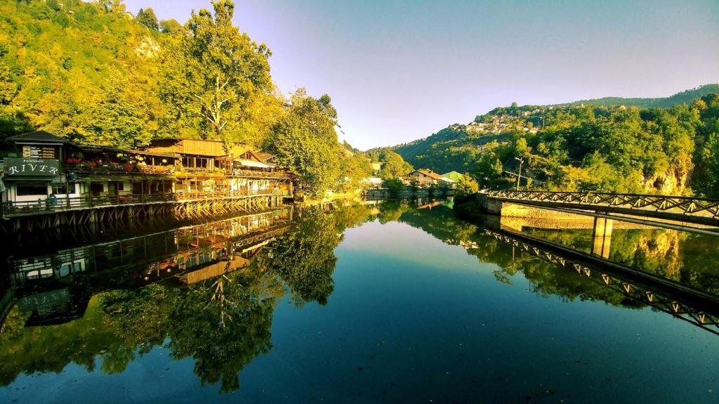 uma vista para um rio com uma ponte e árvores em Pansion River em Saraievo