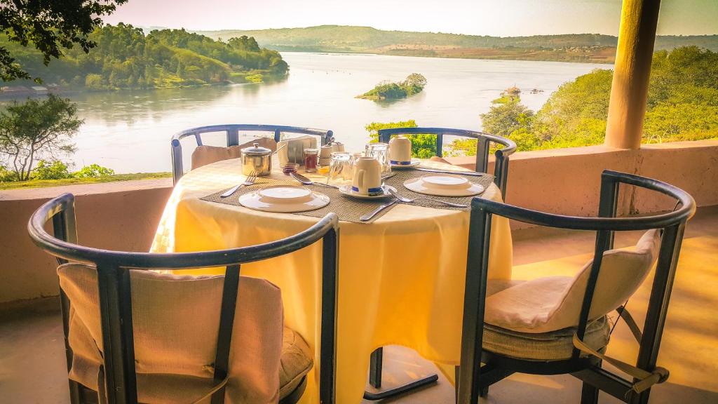 een tafel en stoelen met uitzicht op een rivier bij Living Waters Resort in Jinja