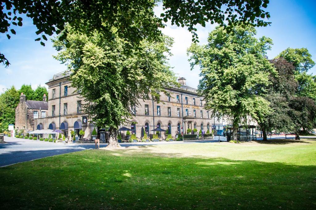 un grand bâtiment avec des arbres devant lui dans l'établissement White Hart Hotel & Apartments, à Harrogate