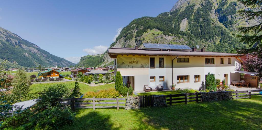 a house in a field with mountains in the background at Apart Alpen in Längenfeld