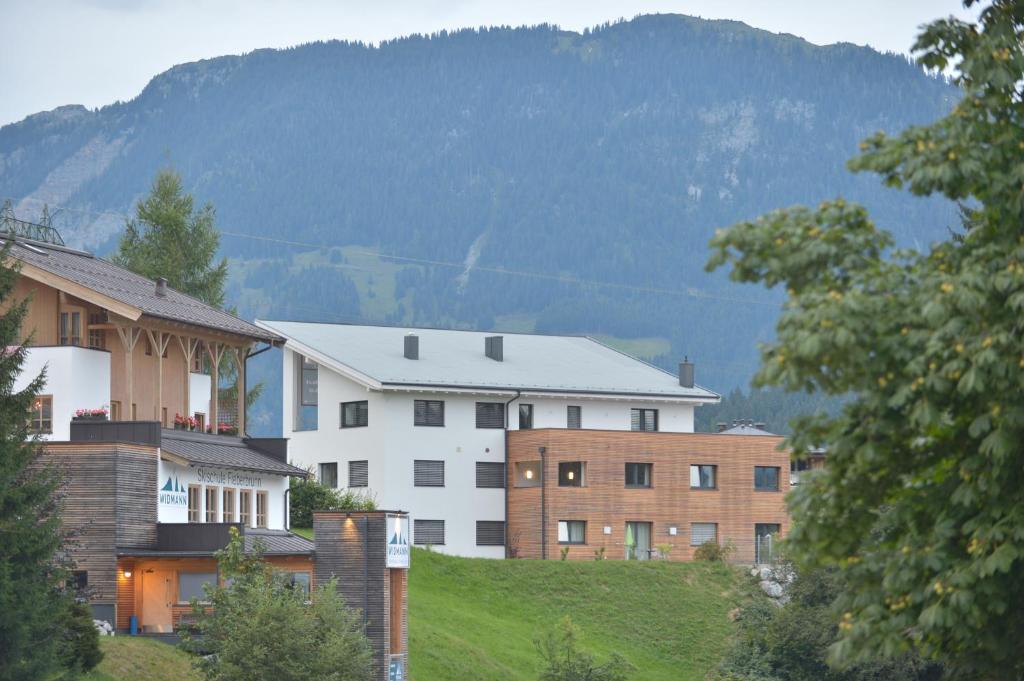 un groupe de bâtiments sur une colline avec une montagne dans l'établissement Haus Kibitz, à Fieberbrunn