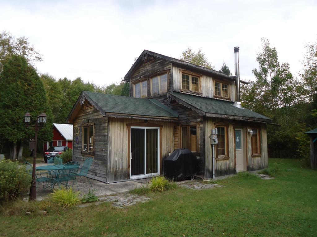 una pequeña casa de madera con un porche en un patio en Chalet Saint-Thomas, en L'Anse-Saint-Jean