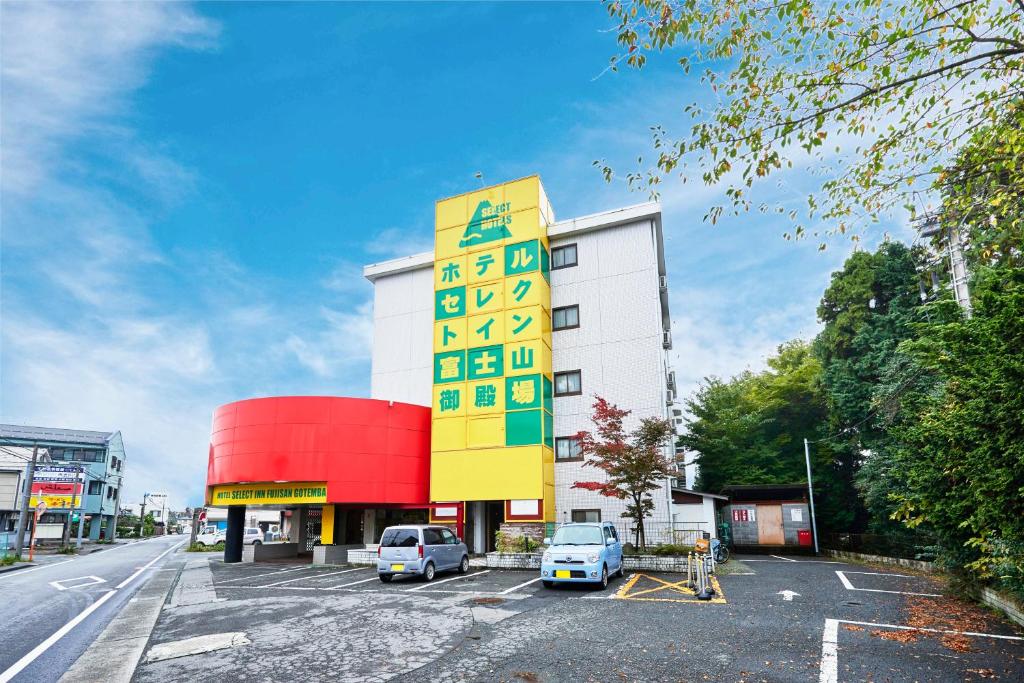 um edifício amarelo e branco com carros estacionados num parque de estacionamento em Select Inn Fujisan Gotemba em Gotemba