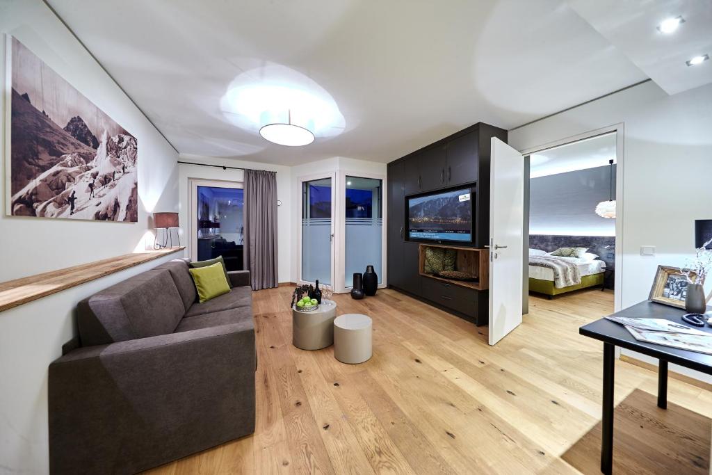 een woonkamer met een bank en een tv bij TWO TIMEZ - Boutique Hotel in Zell am See