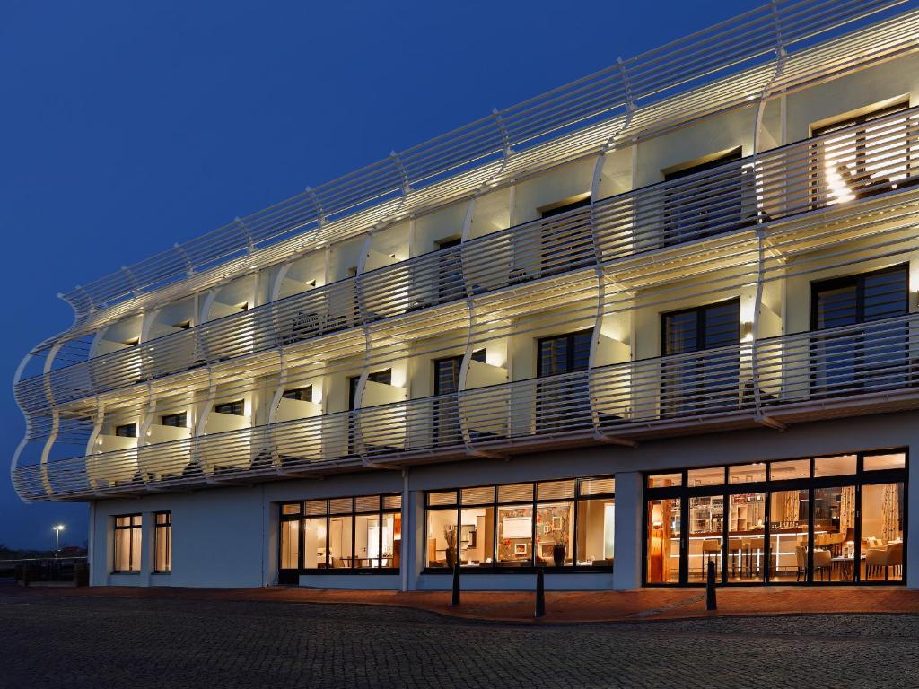 um grande edifício branco com varandas ao lado em Hotel Fährhaus em Norddeich