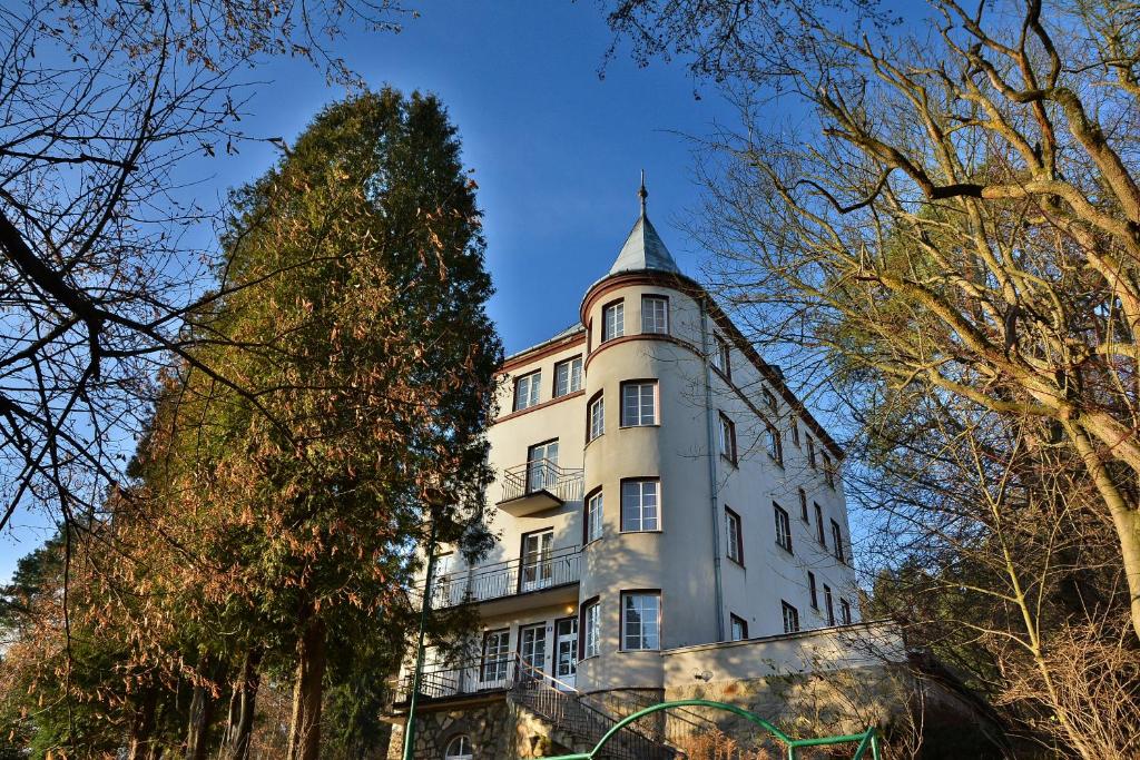 Un alto edificio bianco con una torre sopra. di Rezydencja Zamek a Krynica-Zdrój