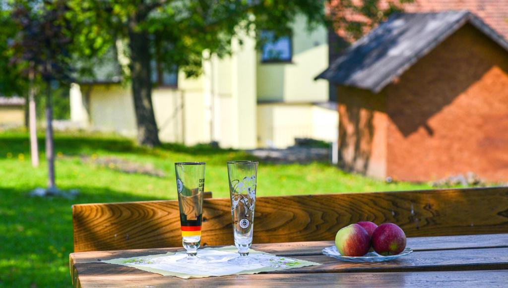 two glasses on a wooden table with apples on it at Sweet Family Home in Cieszyn