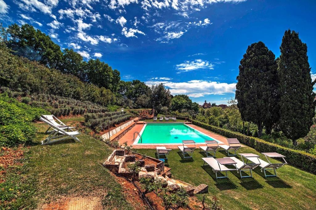 uma vista sobre uma piscina com cadeiras e árvores em Borgo Grondaie em Siena