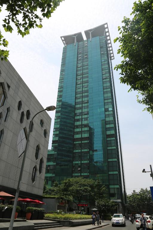 um edifício de vidro alto com pessoas à frente dele em Shanghai Cosmo World Union Service Apartment em Xangai