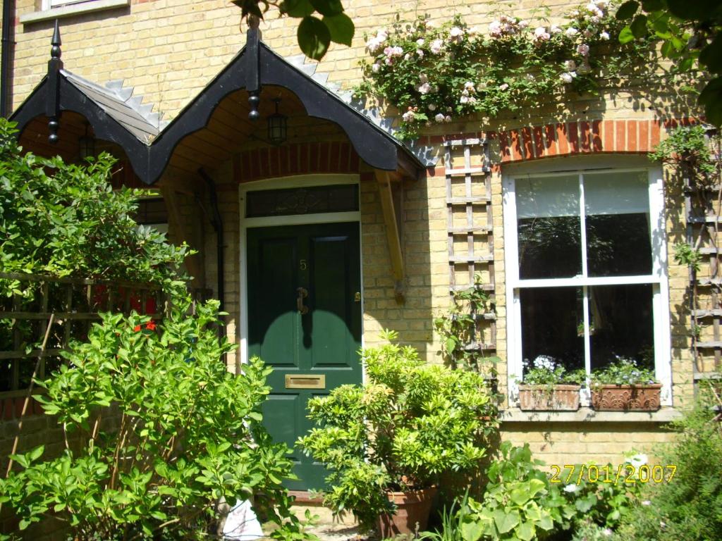 ein Haus mit einer grünen Tür und einem Fenster in der Unterkunft Old Station Gardens, SW London in Teddington