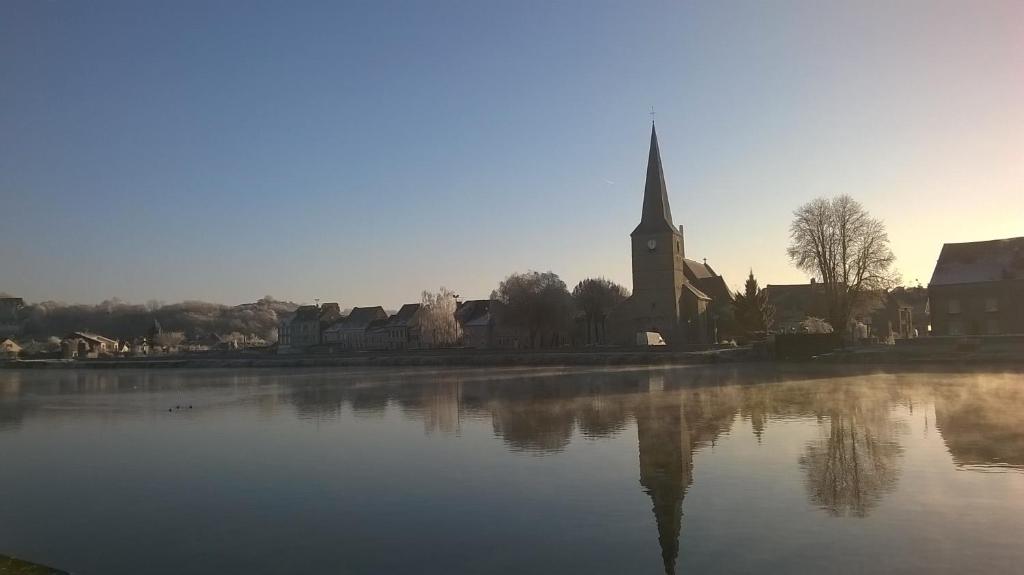 une église et un lac avec une cloche d'église dans l'établissement Hotel Val Saint Hilaire, à Givet