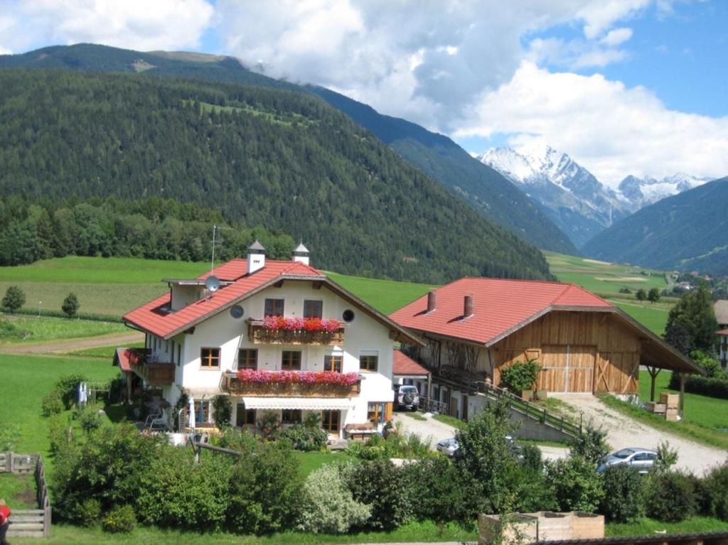 una casa in un campo con montagne sullo sfondo di Appartements Färberhof a Valdaora