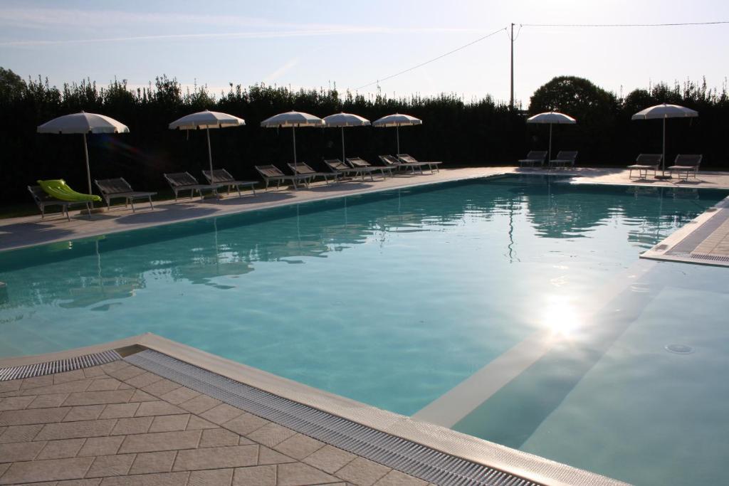 una gran piscina con sillas y sombrillas en Agriturismo La Pisana, en Pisa