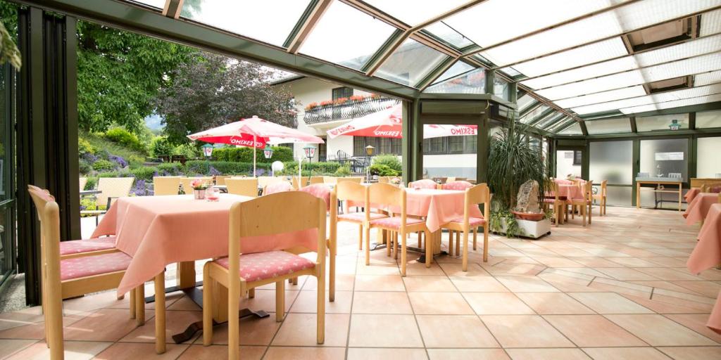 un ristorante con tavoli e sedie rosa in un giardino d'inverno di Flackl - Wirt a Reichenau