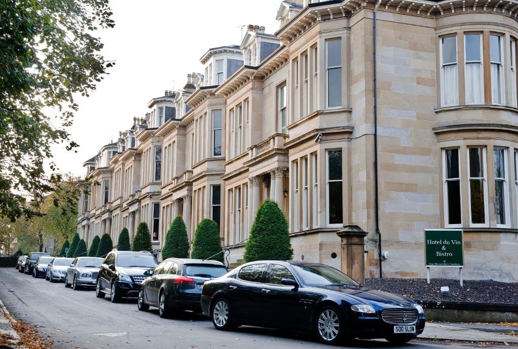 eine Reihe von Autos, die vor einem Gebäude geparkt sind in der Unterkunft One Devonshire Gardens a Hotel Du Vin in Glasgow