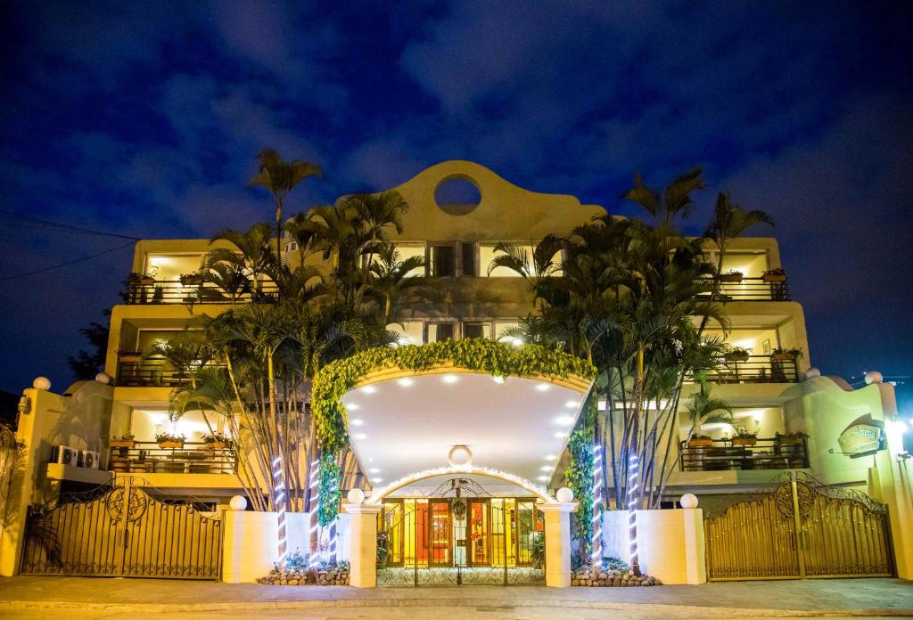 un bâtiment avec une entrée à l'avant et des palmiers à l'avant dans l'établissement Apart-Hotel Casa Serena, à Guatemala