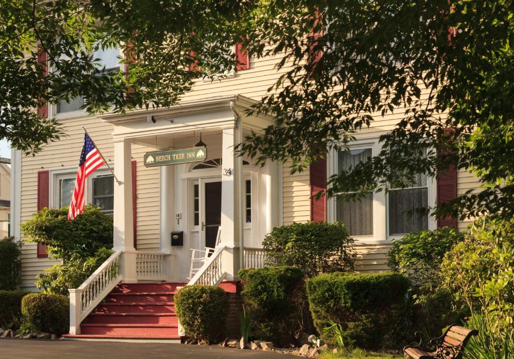 une maison blanche dotée d'un drapeau américain devant elle dans l'établissement Beech Tree Inn and Cottage, à Newport