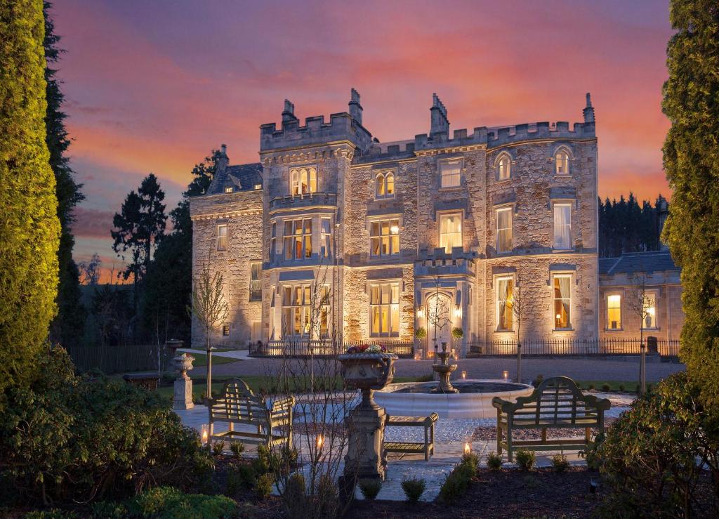 een oud stenen huis met een fontein ervoor bij Crossbasket Castle in High Blantyre