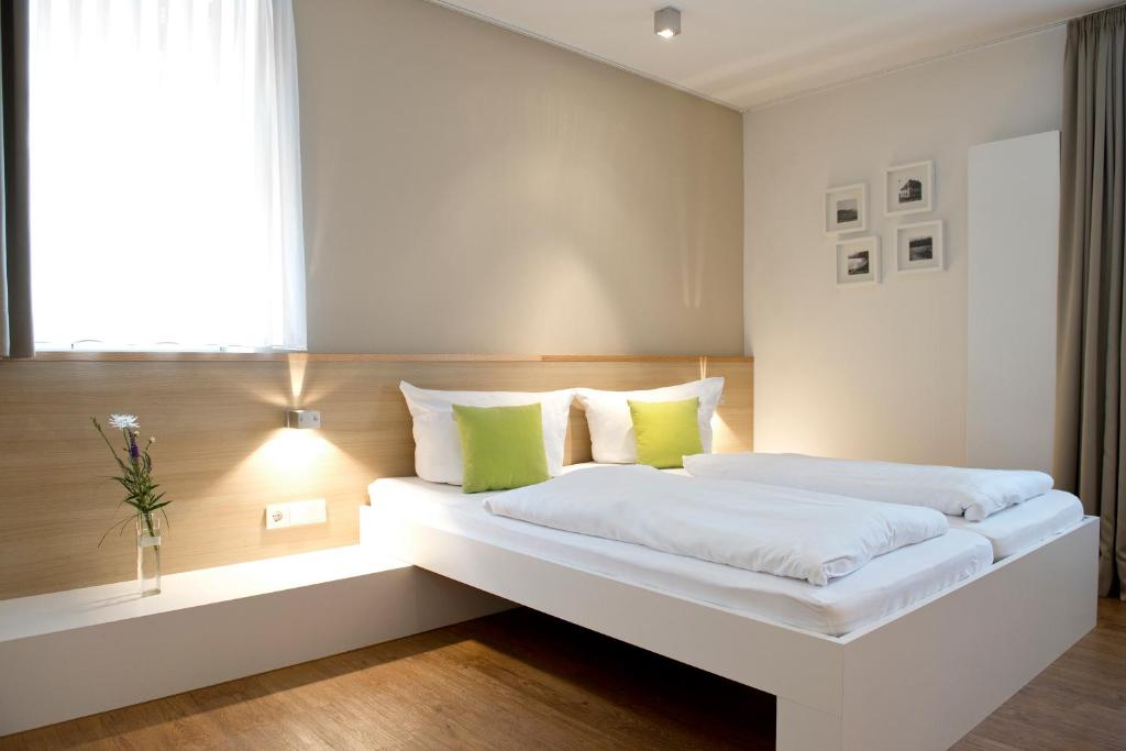 a bedroom with a large white bed with green pillows at Volkspark in Bamberg