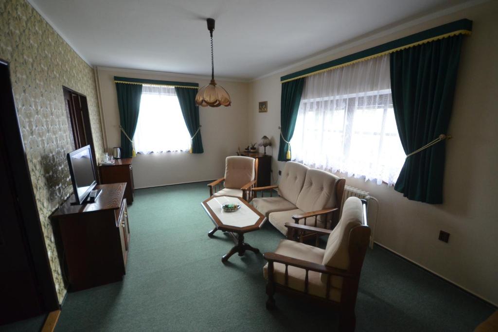 a living room with a couch and chairs and a tv at Villa Žerotín Penzion Bed & Breakfast in Velké Losiny