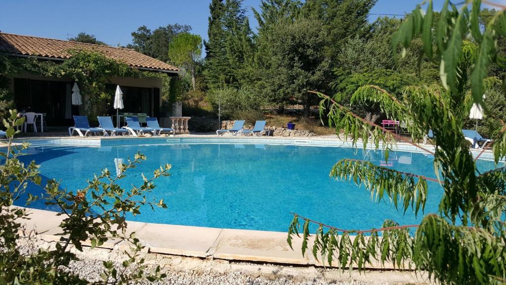 una grande piscina con sedie e una casa di La Cigale a Les Arcs-sur-Argens