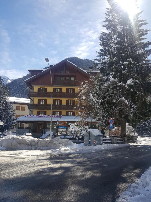 um grande edifício com neve em frente em Hotel Pineta em Ponte di Legno