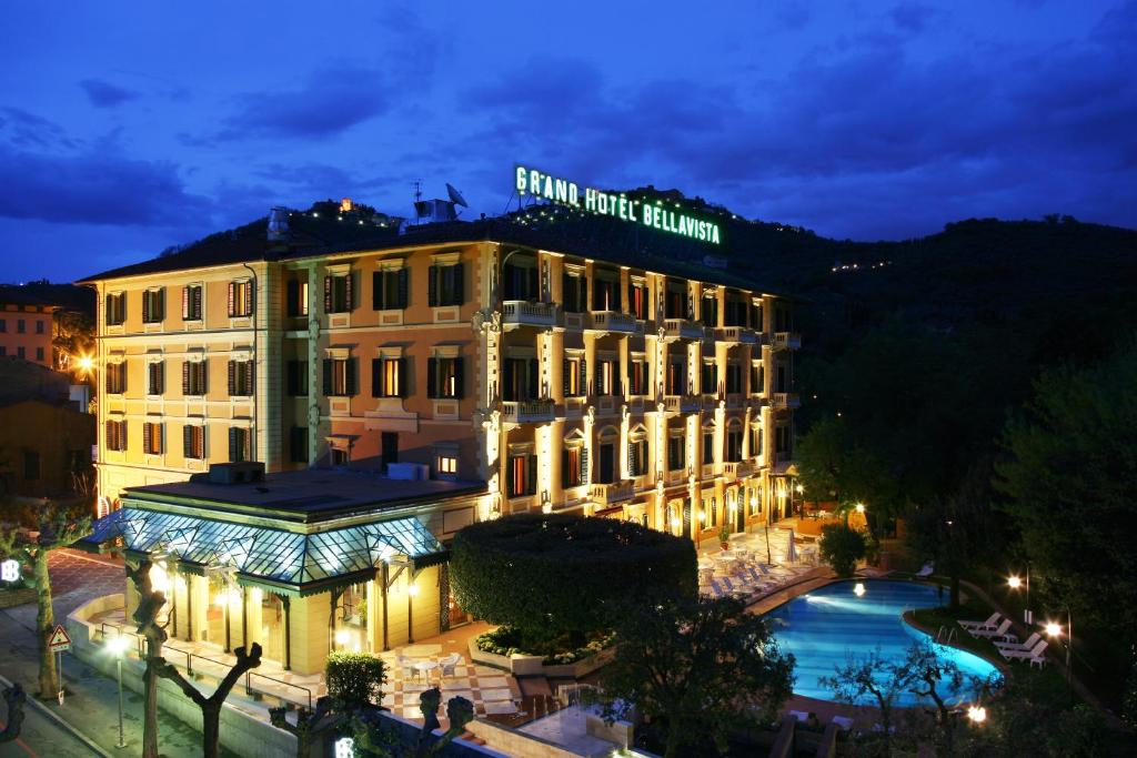 un edificio con una piscina di fronte ad essa di notte di Grand Hotel Bellavista Palace & Golf a Montecatini Terme