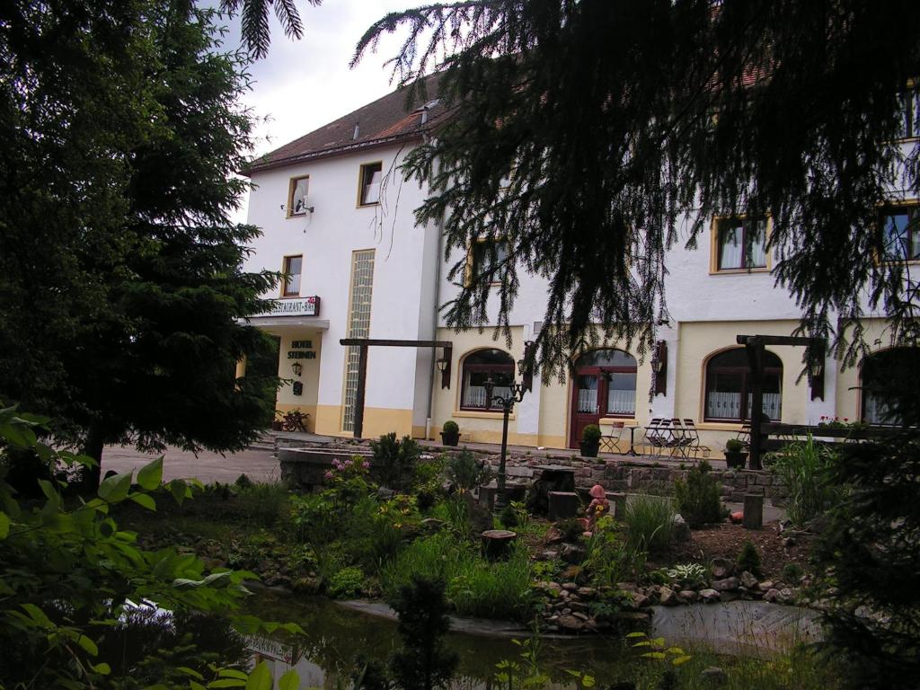 - un bâtiment blanc avec un jardin en face dans l'établissement Hotel Sternen, à Lenzkirch