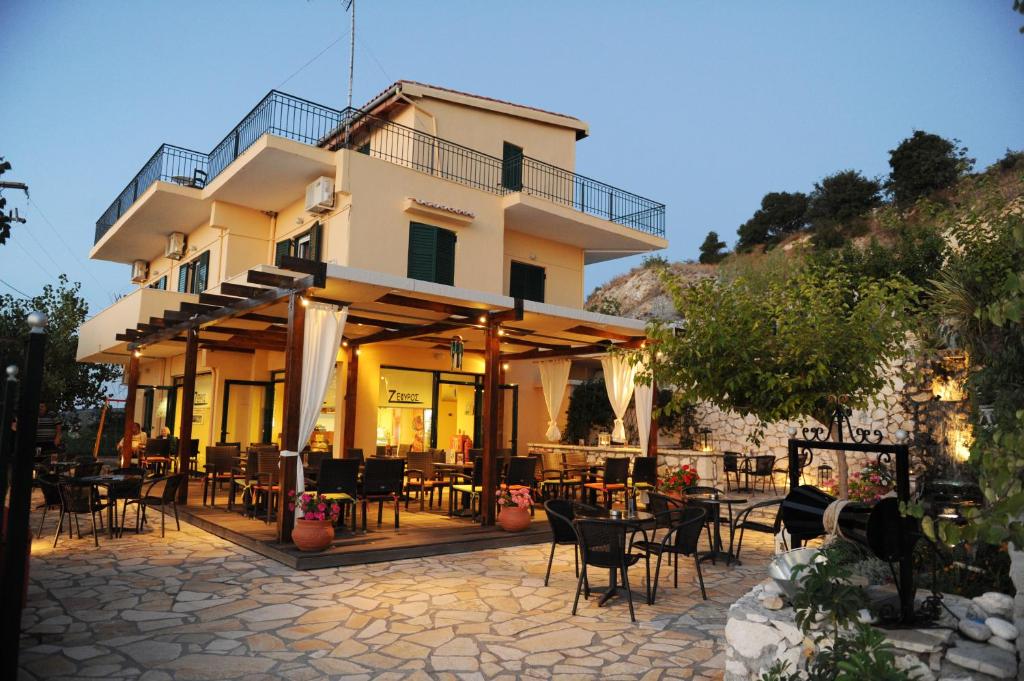 a building with tables and chairs in front of it at Zephyros Rooms And Apartments in Drymon