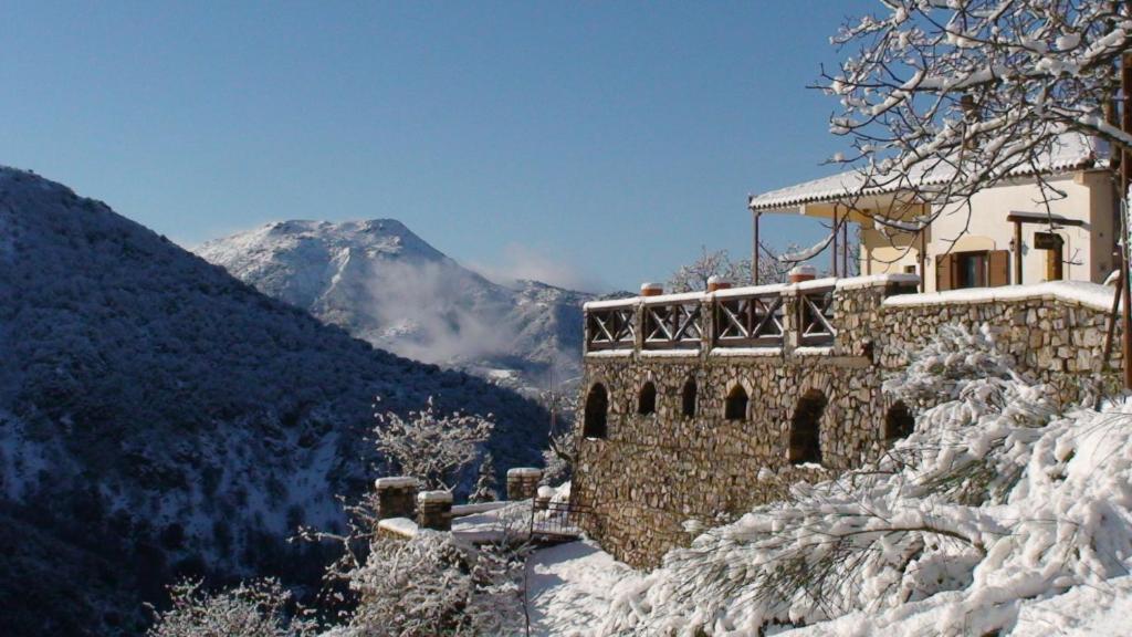 um edifício na neve com uma montanha ao fundo em Agnantio studios & suites em Lagadia