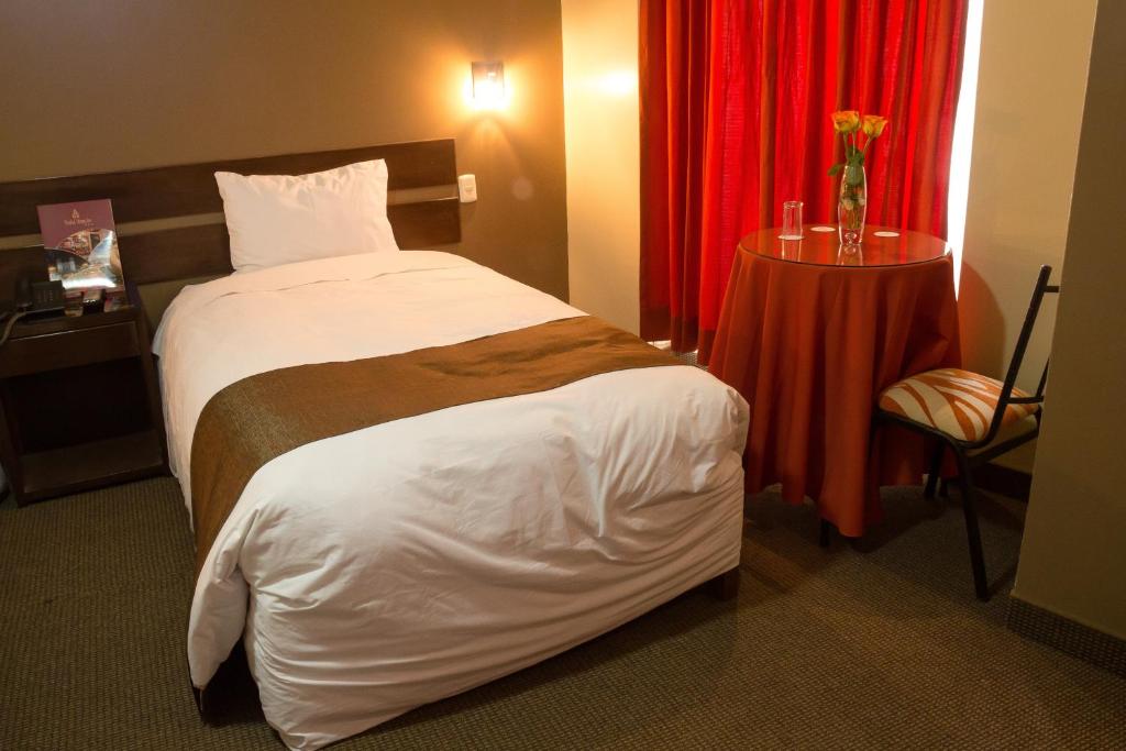 a hotel room with a bed and a red curtain at UTASA VILLA REAL inn in Puno