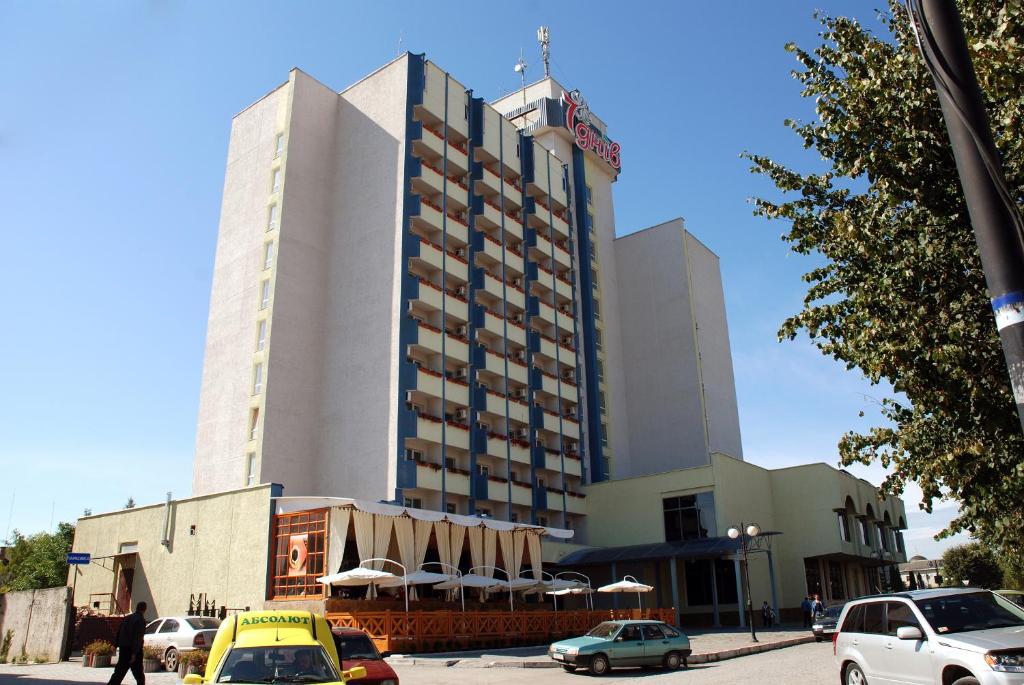 un grande edificio con macchine parcheggiate di fronte di 7 Days Hotel Kamyanets-Podilskyi a Kam"janec'-Podil's'kyj