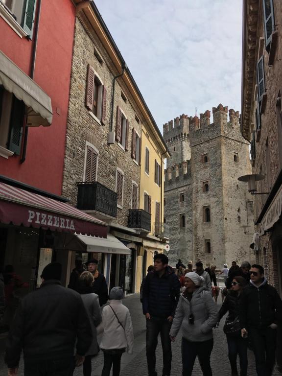 um grupo de pessoas andando por uma rua com um castelo em Aurora Sirmione Appartamenti em Sirmione