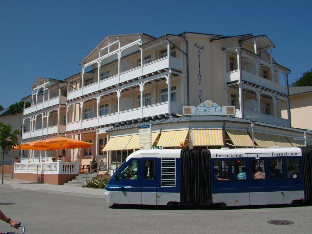 un treno bianco e blu di fronte a un edificio di Hotel Selliner Hof a Ostseebad Sellin