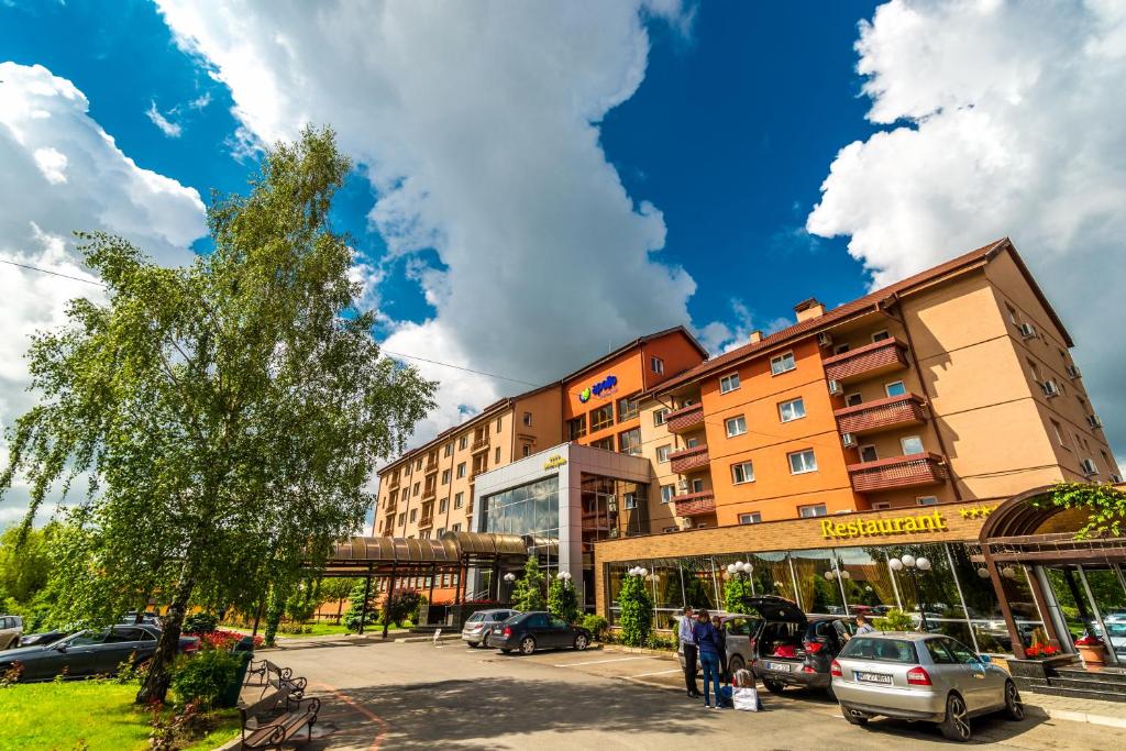 un edificio con auto parcheggiate in un parcheggio di Apollo Wellness Club a Sângeorgiu de Mureș