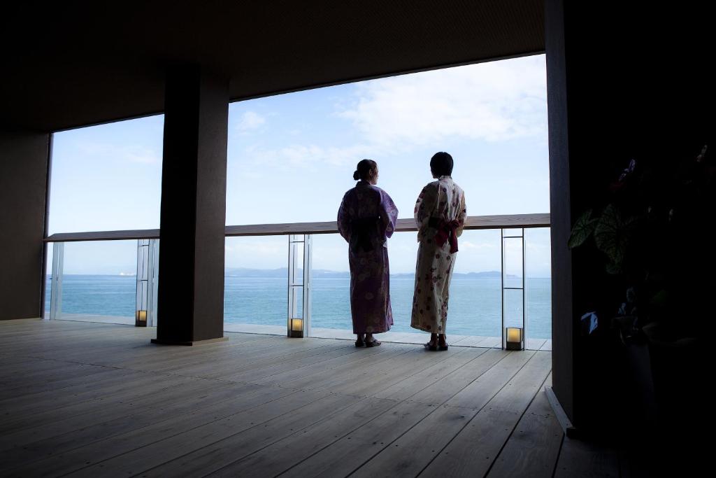 duas pessoas de pé numa varanda com vista para o oceano em Hanagoyomi em Sumoto