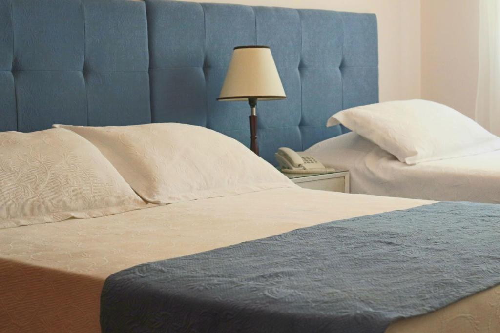 uma cama com uma cabeceira azul ao lado de um telefone em Hotel San Martin em Punta del Este