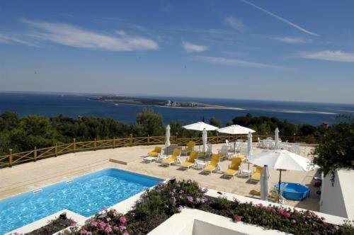 een zwembad met stoelen en parasols en de oceaan bij Quinta Dos Moinhos De Sao Filipe in Setúbal