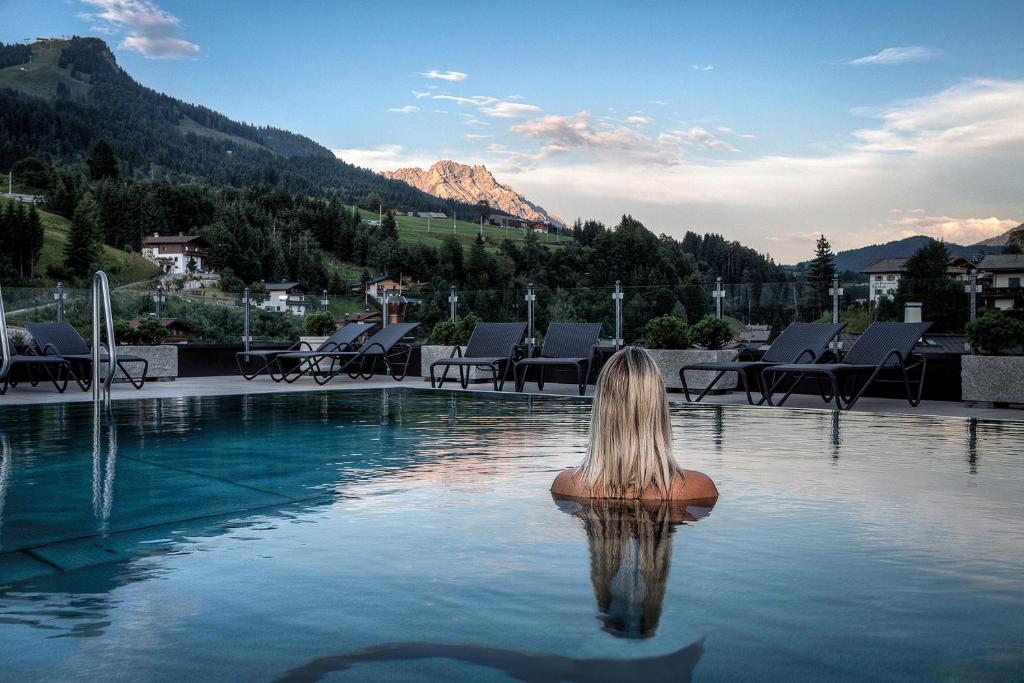 une femme assise à l'eau dans une piscine dans l'établissement Hotel Alte Post, à Fieberbrunn